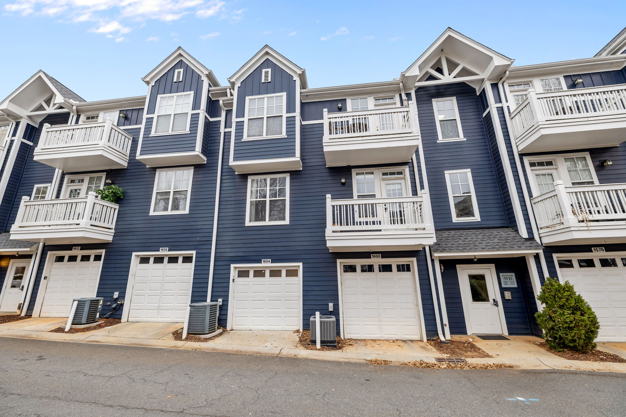 Front exterior of townhome with blue siding and white balconies